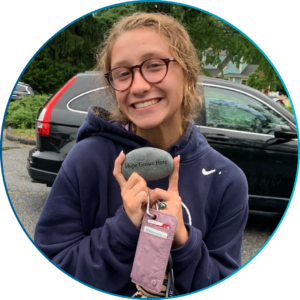 A photo of Abby holding a rock that says "Hope Grows Here".